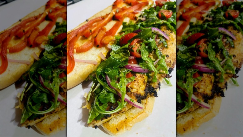 Blackened seabass on roll with arugula, tomato, red onion, and red peppers