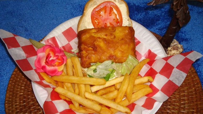 Open-faced fish sandwich with tomato and lettuce in basket with fries