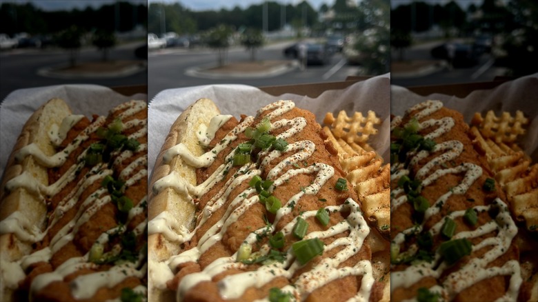 Open fish sandwich with tartar sauce drizzle and green onions on sub roll