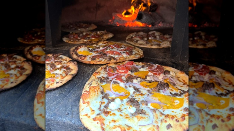 Several pizzas in front of a wood fire