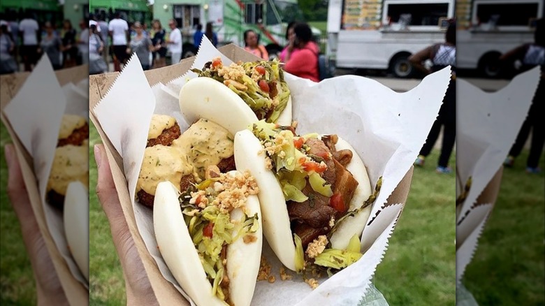 Hand holding tray with baowich in front of food truck