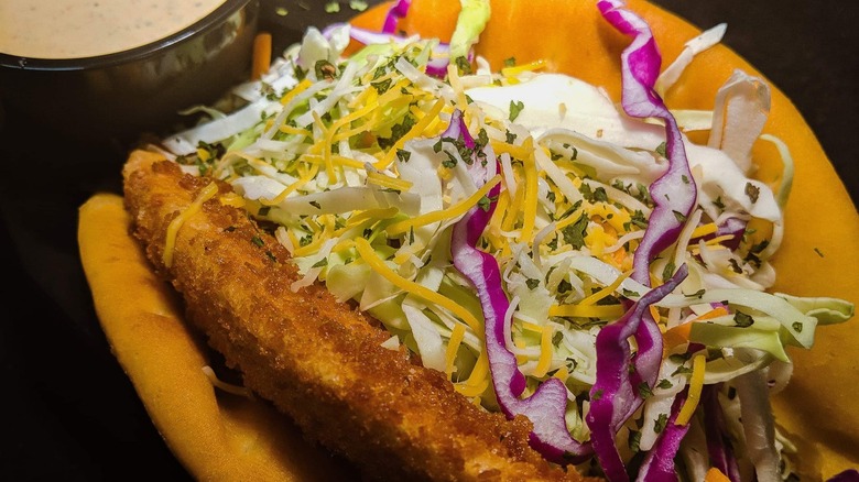 Fried fish taco with slaw and side of sauce