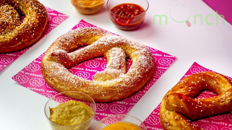 Three soft pretzels on wrappers with sauces