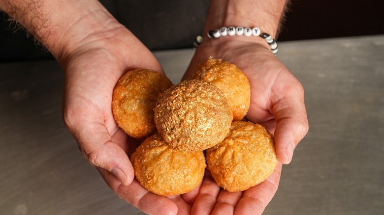 Hands holding five dumplings