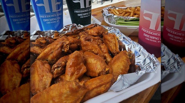 Order of Buffalo wings in take-out container with drinks