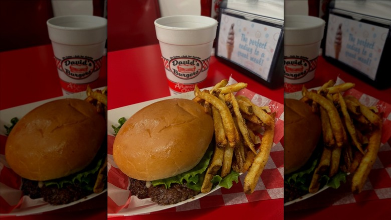 Burger and fries in front of David's Burgers cup on red table