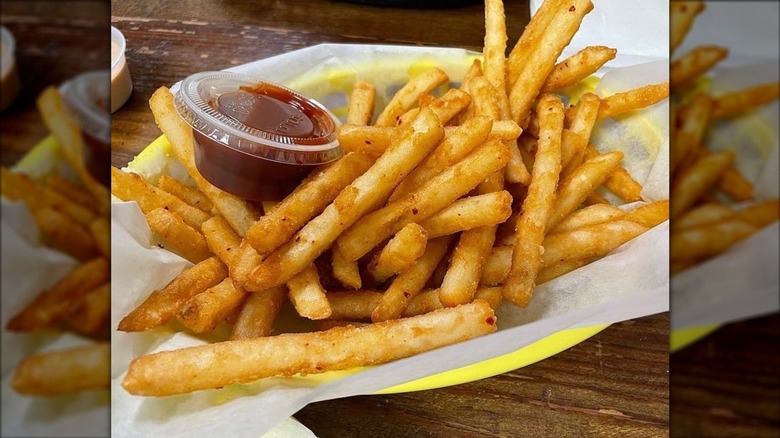 Fries in basket next to cup of ketchup