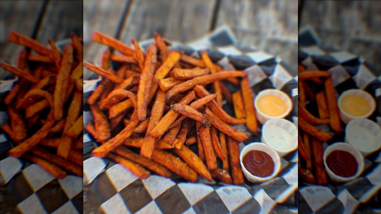 Sweet potato fries next to three sauces in basket
