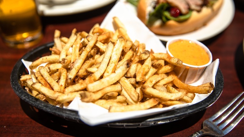 Black basket of fries with side cup of sauce