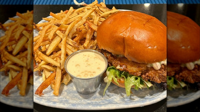 Fried chicken sandwich, fries, and sauce on plate