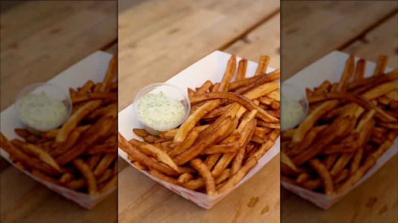 Basket of fries and sauce on wooden table