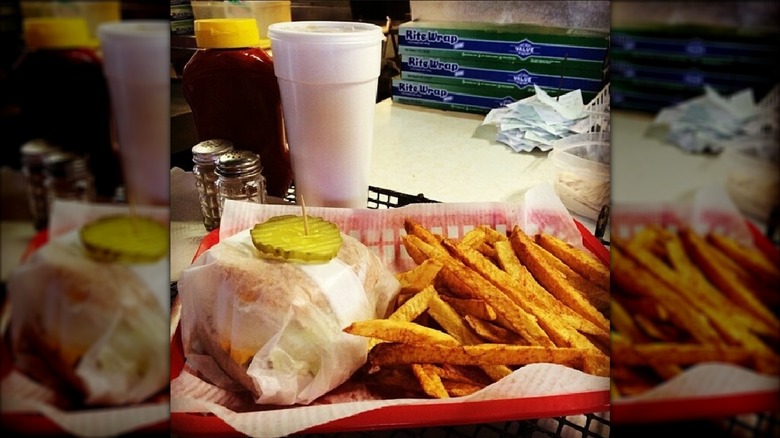 Fries next to paper-wrapped burger in red basket