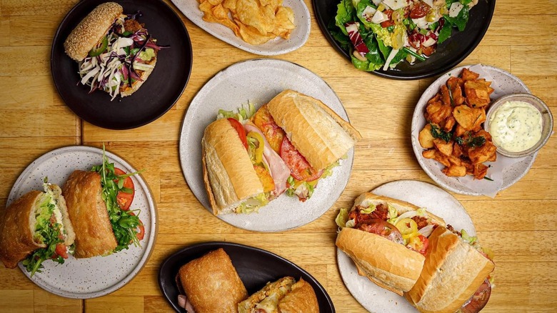 Assorted sandwiches, salads, and chips on wooden table