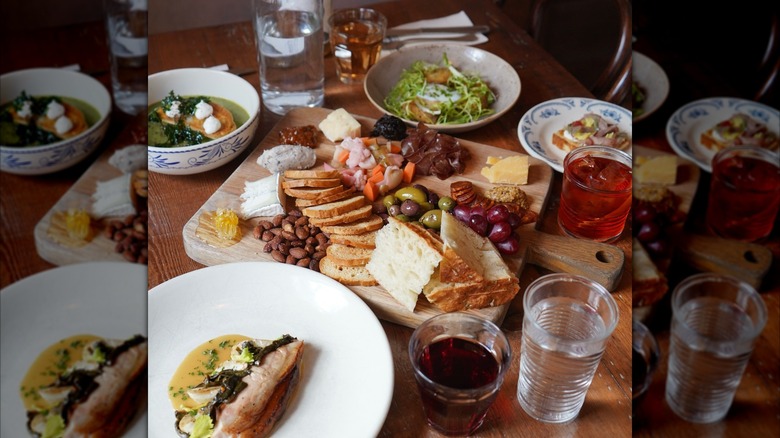 Table set with charcuterie board, drinks, soup, and salads