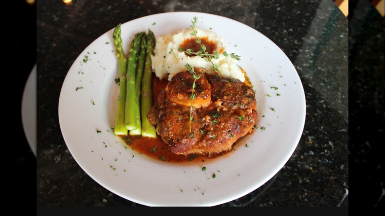 Veal osso bucco with asparagus and mash on white plate