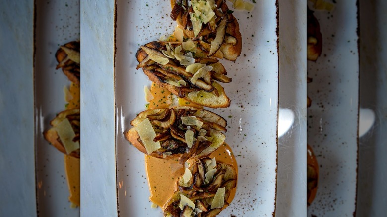 Mushroom crostini with aioli on white plate