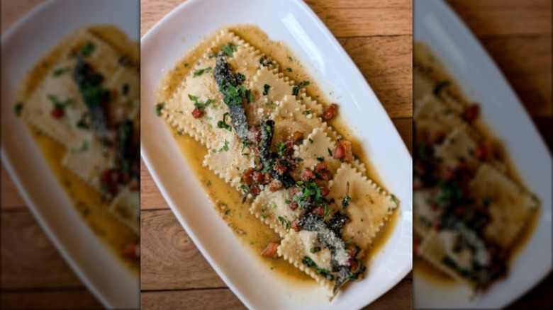 Ravioli with brown butter on white plate and wooden table