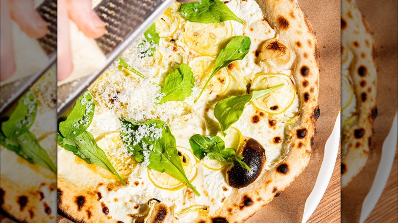 Parm being grated on white pizza with basil