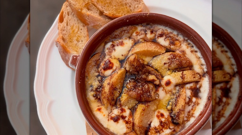 Pear gratin with slices of bread in rown bowl on white plate