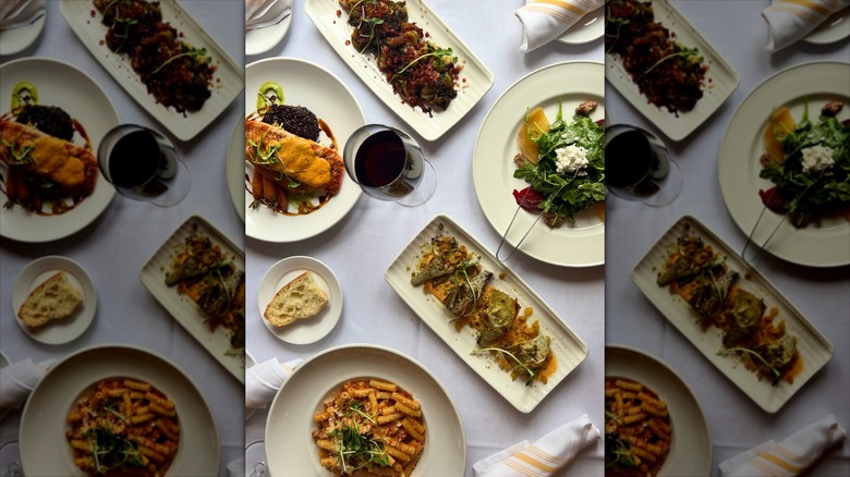 Assortment of pastas and dishes on white table with glasses of wine