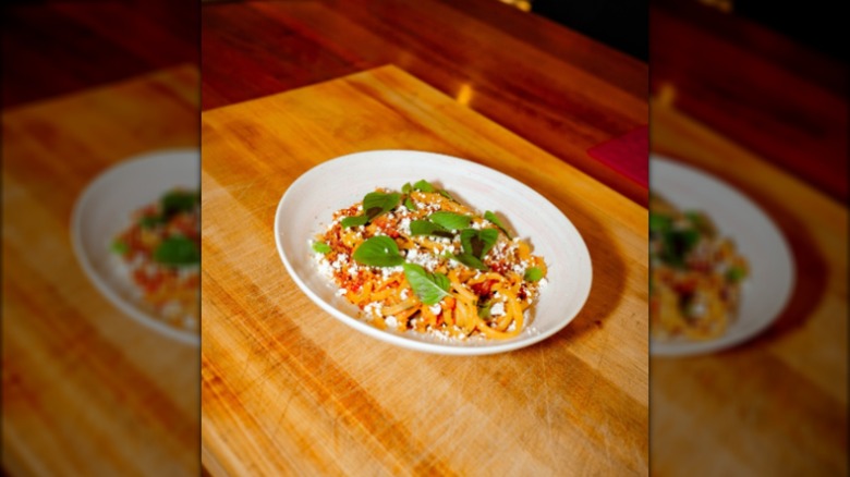 Dish of spaghetti with fresh basil and cheese on wooden table