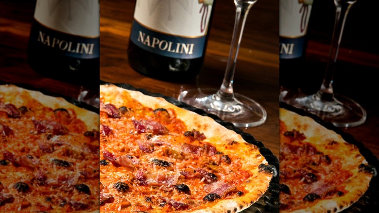 Wod-fired pizza with glass and bottle of wine in the background