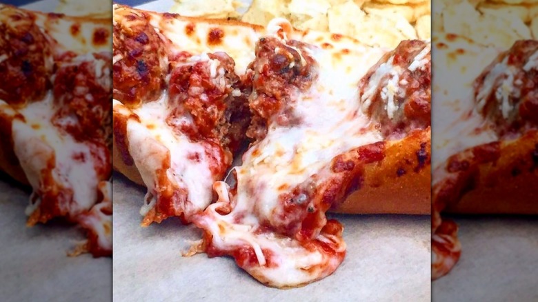 Meatball sub with cheese and sauce running over roll