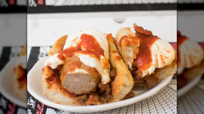 Two halves of a meatball sub on a plate with black and white table