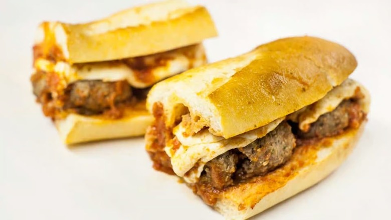 Two halves of meatball sub on white background