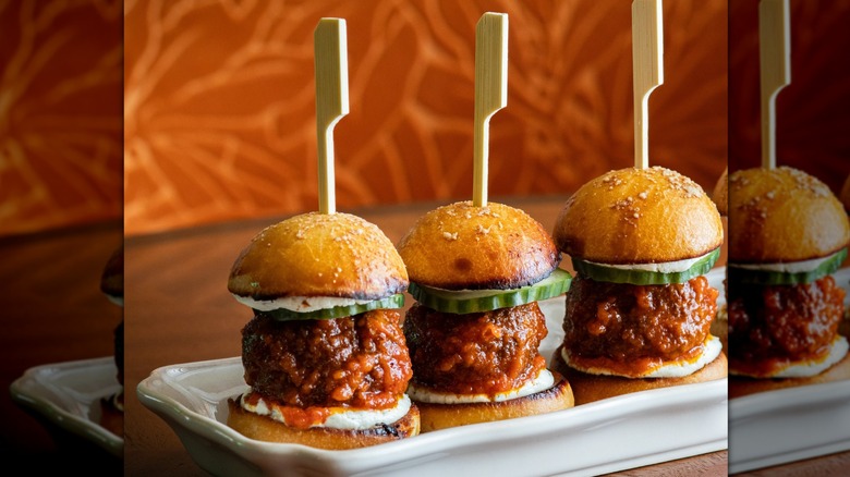 White plate with three lamb sliders with cucumber