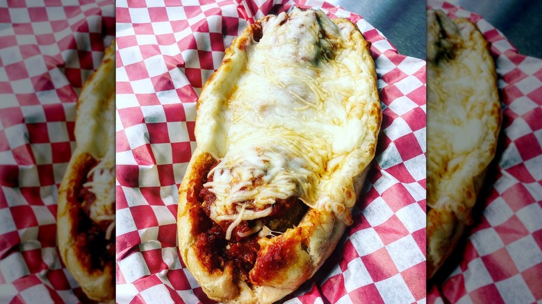 Full meatball sub with lots of cheese on red and white paper wrap