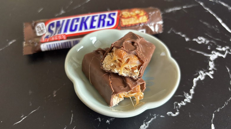 An original Snickers split in half, with the wrapper in the background