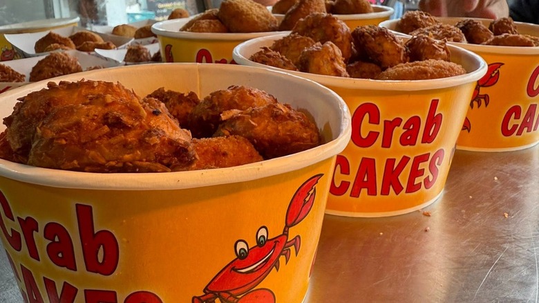 Buckets of deep-fried crab cakes on stainless steel table