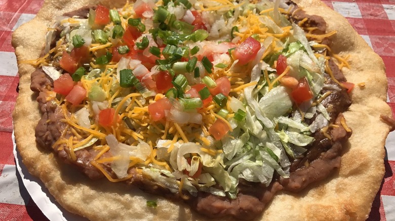 Frybread with refried beans, lettuce, tomatoes, onions, and cheese