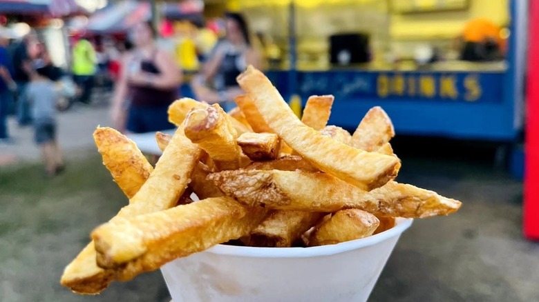 Cup of fries in front of blurred blue and yellow stand