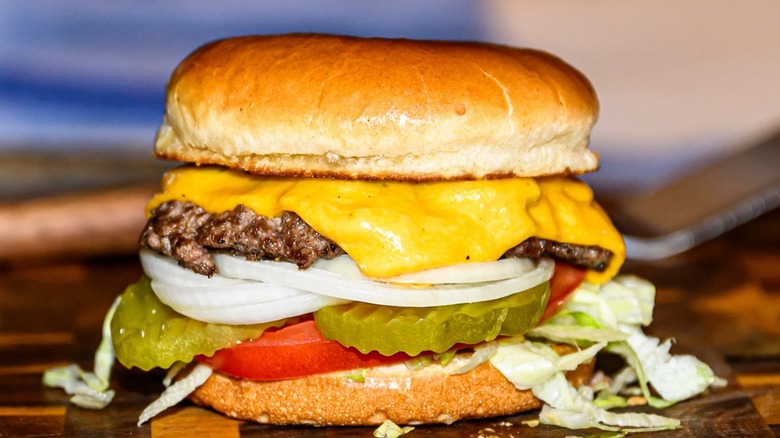 Cheeseburger on board with onions, picked, and tomato
