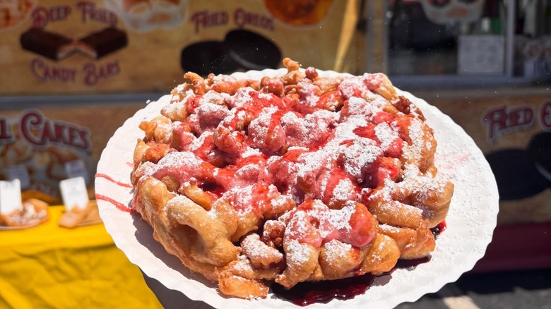 Funnel cake with sugar and Cheerwine drizzle in front of blurred truck