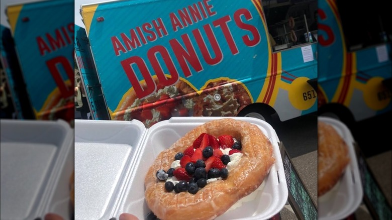 Giant donut with fruit in container in front of Amish Annie Donuts truck