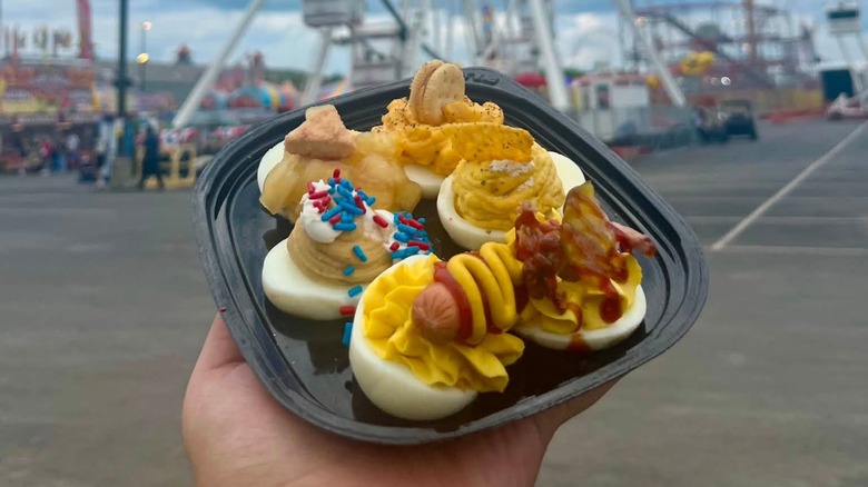 Hand holding assorted deviled eggs in a tray