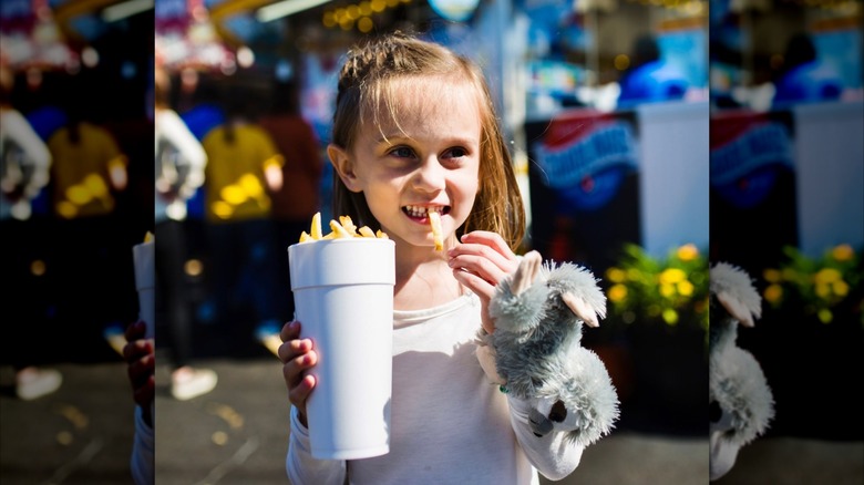 Little kid eating fries out of a styrofoam cup