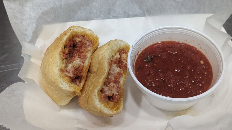 Pepperoni roll cut in half with cup of sauce