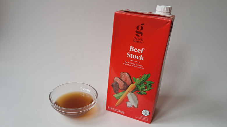 A carton of Good & Gather Beef Stock sitting next to a small glass bowl of the broth