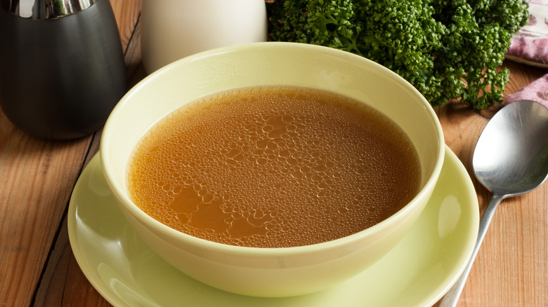 A white bowl of beef broth on a table