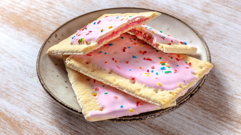 Three strawberry toaster pastries on a plate with sprinkles and pink icing