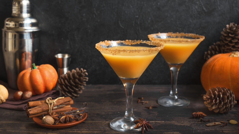 two orange drinks in martini glasses with cinnamon sugar rim