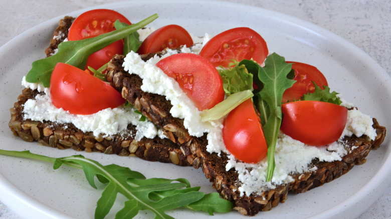 Cottage cheese on seeded rye bread with chopped tomatoes and arugula