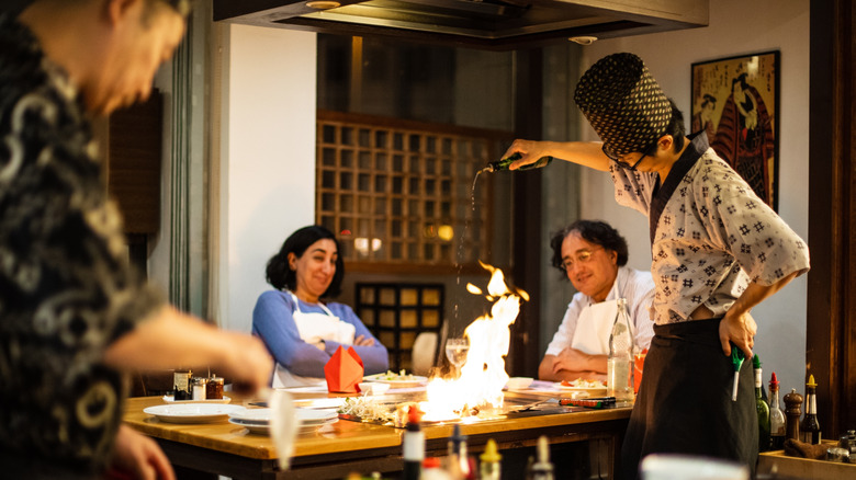 Customers recoil as oil flames on the hibachi table in front of them