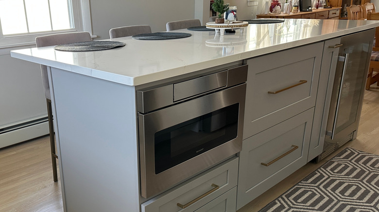 Stainless steel microwave installed in a gray kitchen island