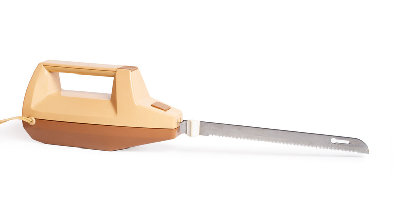 a vintage two-tone electric knife against a white background