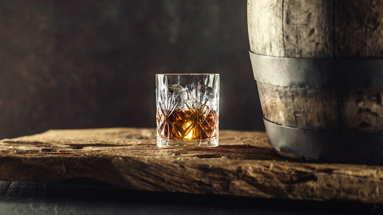 Glass ob bourbon next to barrel